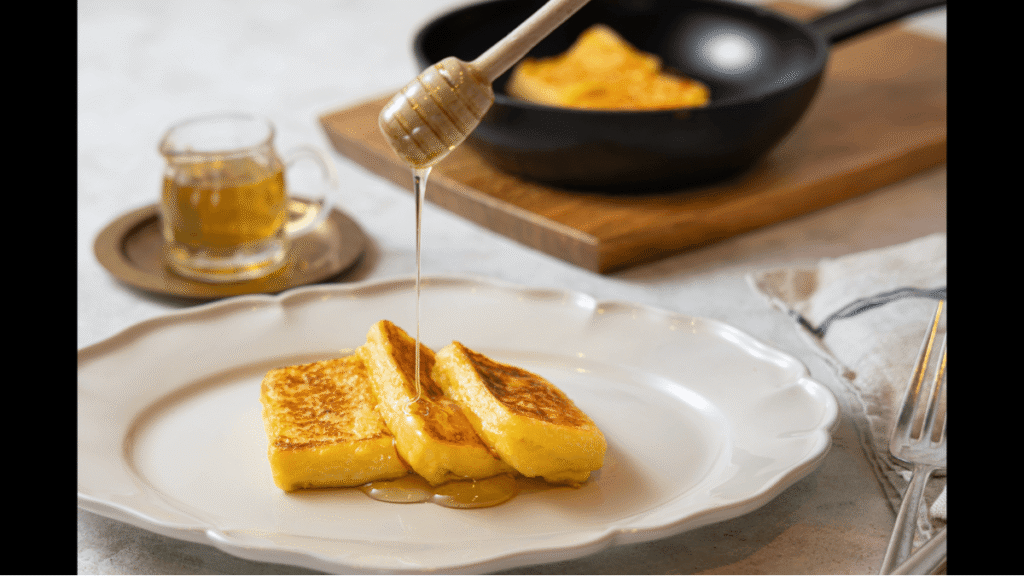 ホテルオークラ東京ベイの名物朝食、フレンチトーストのプレート。厚切りのパンに粉糖がまぶされ、メープルシロップとホイップクリーム、イチゴとブルーベリーが添えられている。