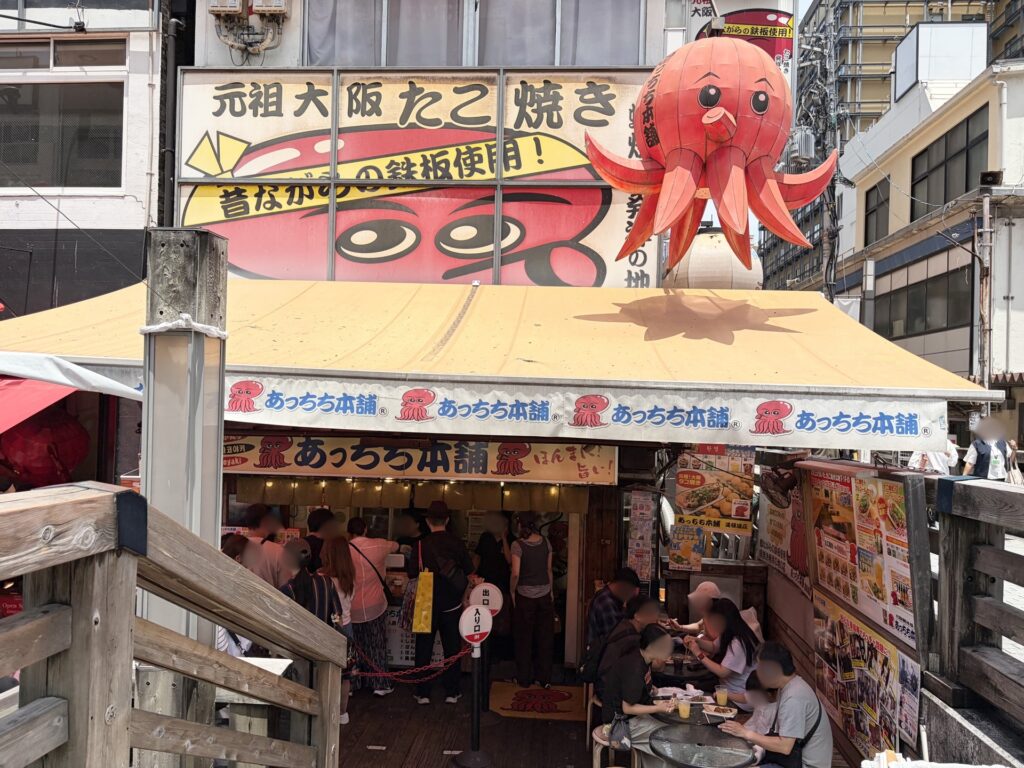 Atchi-chi Honpo takoyaki stand exterior in Dotonbori, Osaka — popular spot, expect a short queue