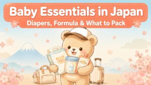 Bear mascot illustration for a Japan baby travel guide, holding diapers, formula, and baby food with Mt. Fuji and cherry blossoms in the background