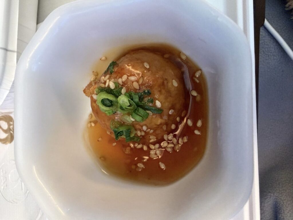 JAL機内食の副菜、鶏肉団子。あんかけだれに白ごまと小葱がのった一品