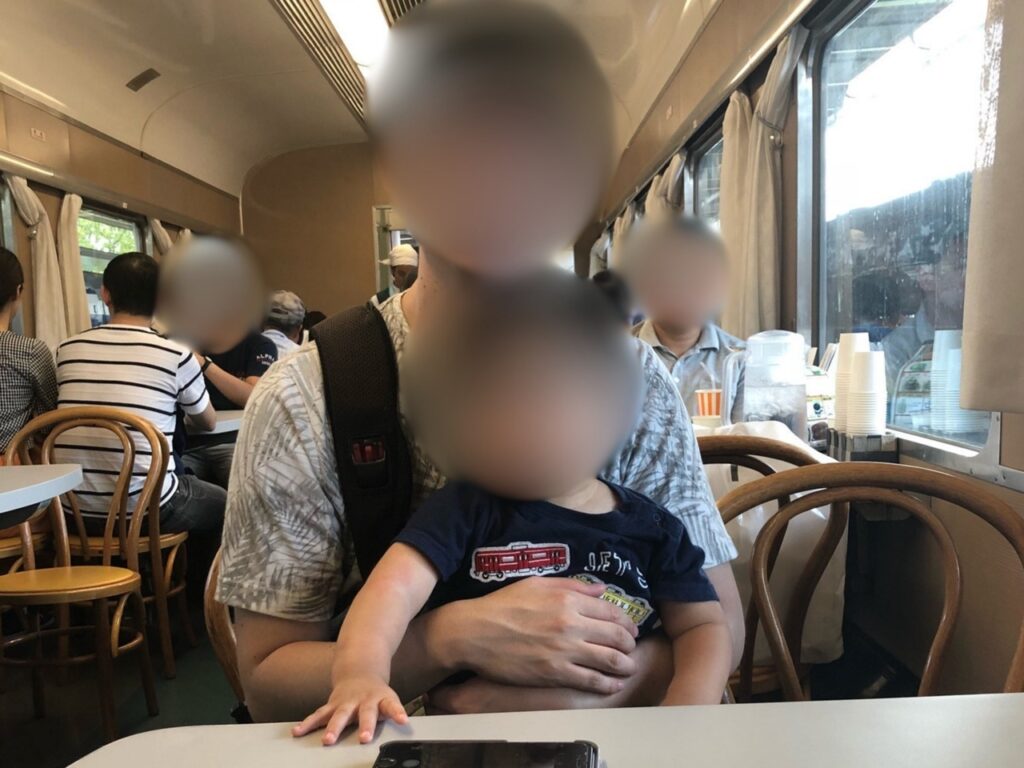 Family having lunch inside the preserved dining car at Kyoto Railway Museum, with the retro interior and snack counter visible.