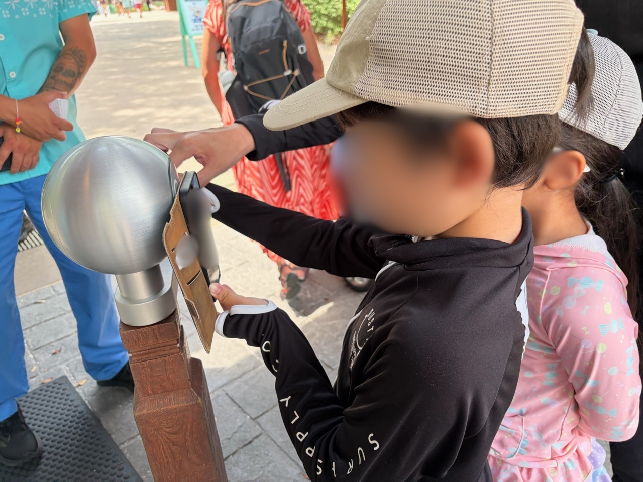 WDWの入園ゲートで、子供が中古スマホに入れた入園パスをミッキー型のタッチ機械にかざしている様子