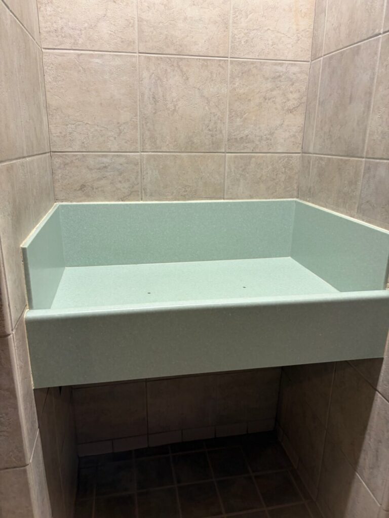 ブリザードビーチのトイレにある据え付けのおむつ替え台。淡いグリーンの台に、落下防止の立ち上がりがついている