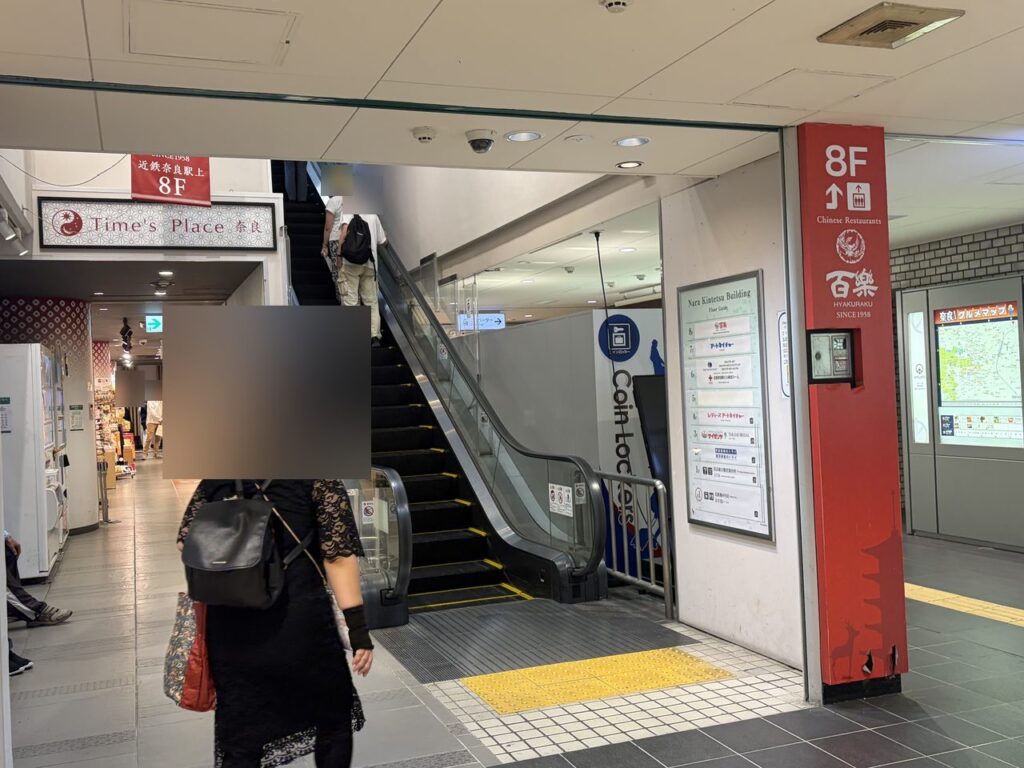 近鉄奈良駅の地上へ上がるエスカレーター。右手に奈良近鉄ビルの案内板とコインロッカーの表示がある
