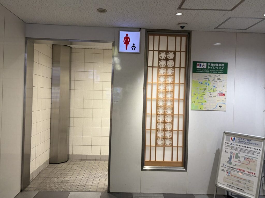 近鉄奈良駅の改札外にある女子トイレの入口。女性マークの下に赤ちゃんのマークが並び、横に奈良公園周辺のトイレマップが貼られている