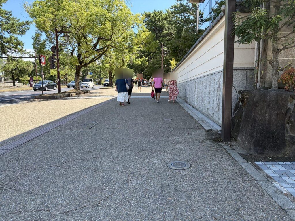 近鉄奈良駅から奈良公園へ向かう歩道。白い塀に沿って平らな道がまっすぐ続いている