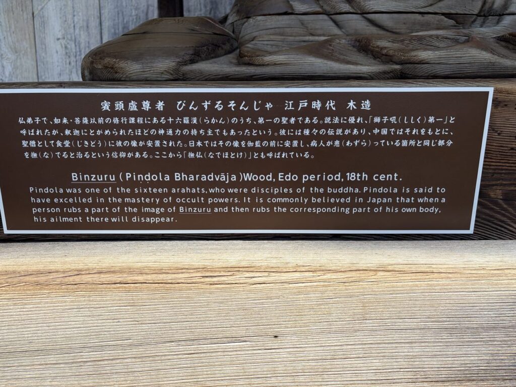 びんずる尊者の説明板。江戸時代の木造で、体の悪いところと同じ場所をなでると治ると言われると日本語と英語で書かれている