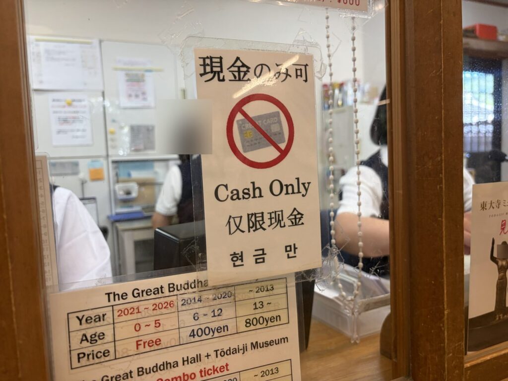 東大寺の入堂券売り場の窓口。「現金のみ可 Cash Only」の貼り紙と、年齢別の料金表が掲示されている