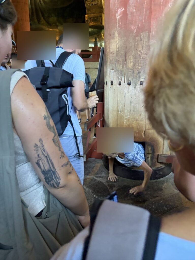 東大寺の柱の穴をくぐろうとしている人と、それを見守る観光客