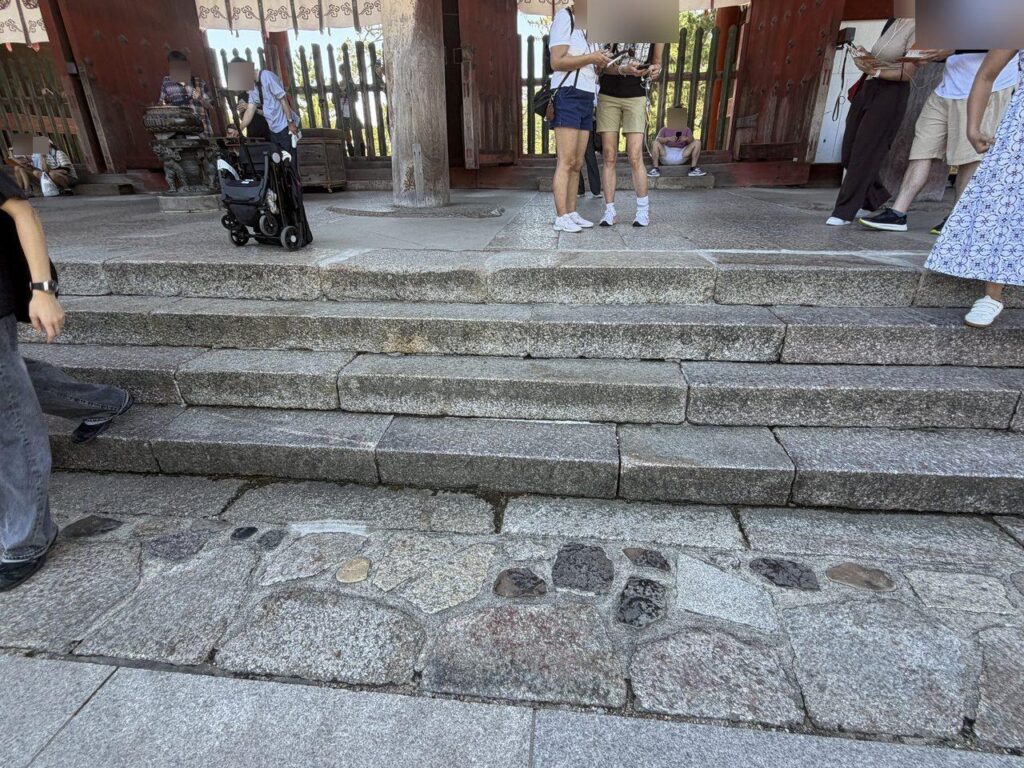 東大寺の回廊の石段を近くから見たところ。3〜4段の段差があり、上の段には折りたたんだベビーカーが置かれている