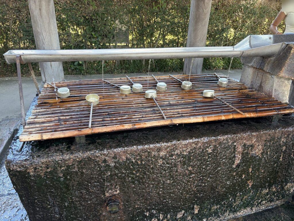 東大寺の手水屋。竹のすのこの上に金属の柄杓がいくつも伏せて置かれ、水が流れている