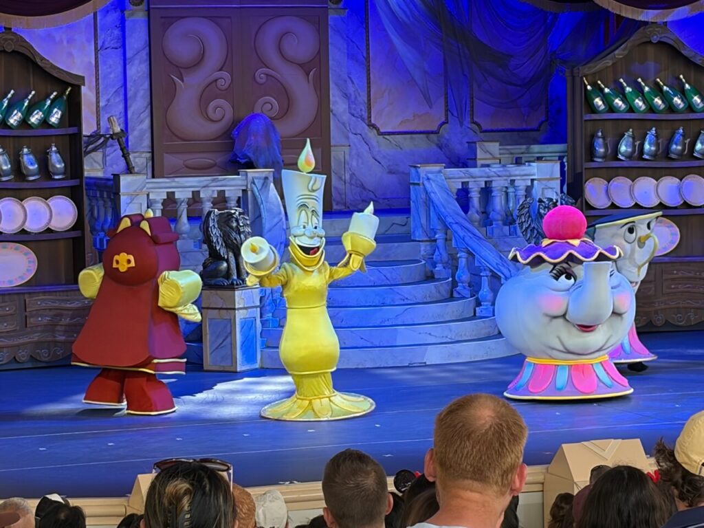 美女と野獣ライブ・オン・ステージの舞台。ルミエール、ポット夫人、チップなどの着ぐるみキャラクターが青い照明の城のセットで踊っている。
