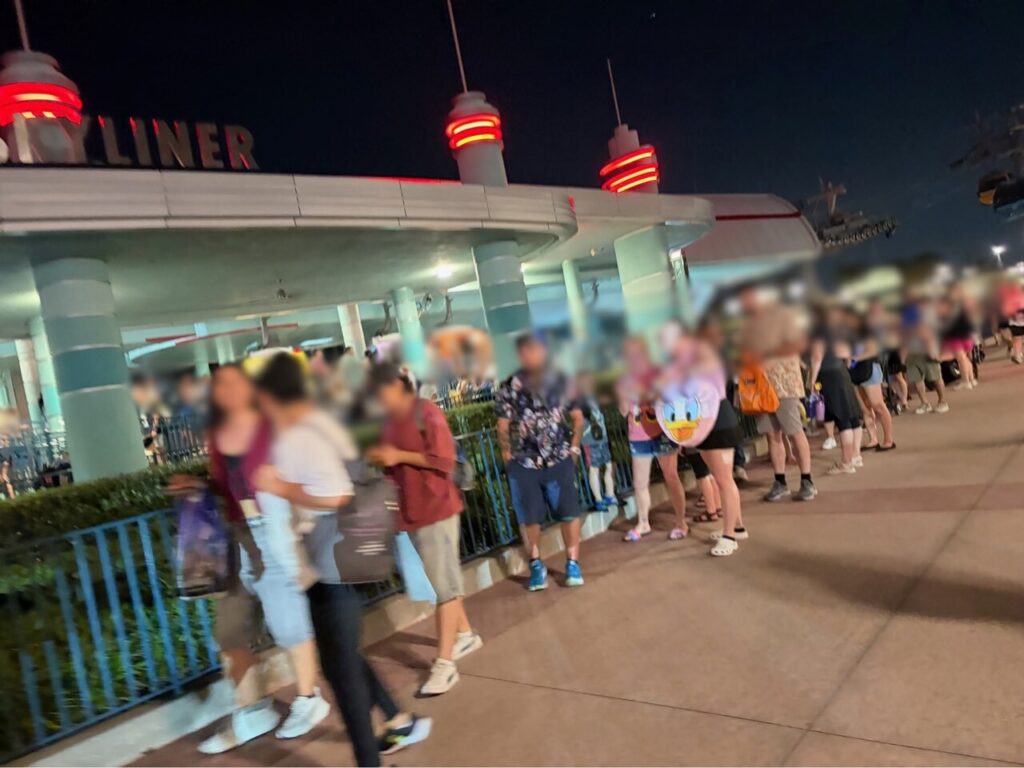 ファンタズミック終了後、夜のスカイライナー乗り場にできた長い列。SKYLINERのネオン看板の下に多くのゲストが並んでいる(顔はぼかし処理)。