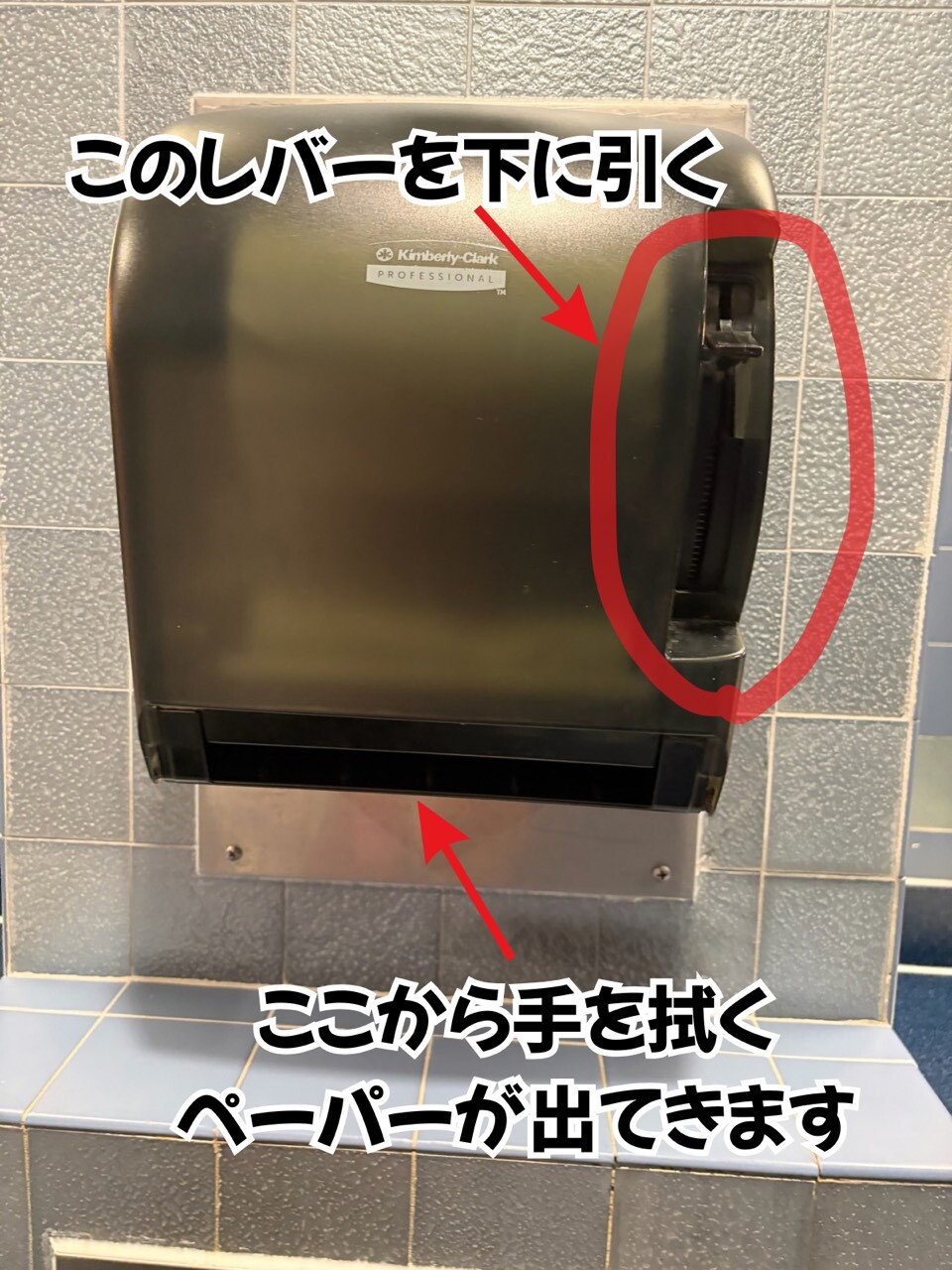 アメリカのトイレの手拭きペーパーディスペンサー。レバーを下に引くと紙が出る解説入り